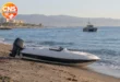 Abandoned speedboat on a beach with patrol boat offshore